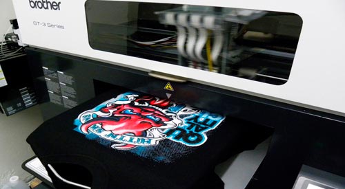 máquina de estamparia digital direta imprimindo em camiseta preta já costurada